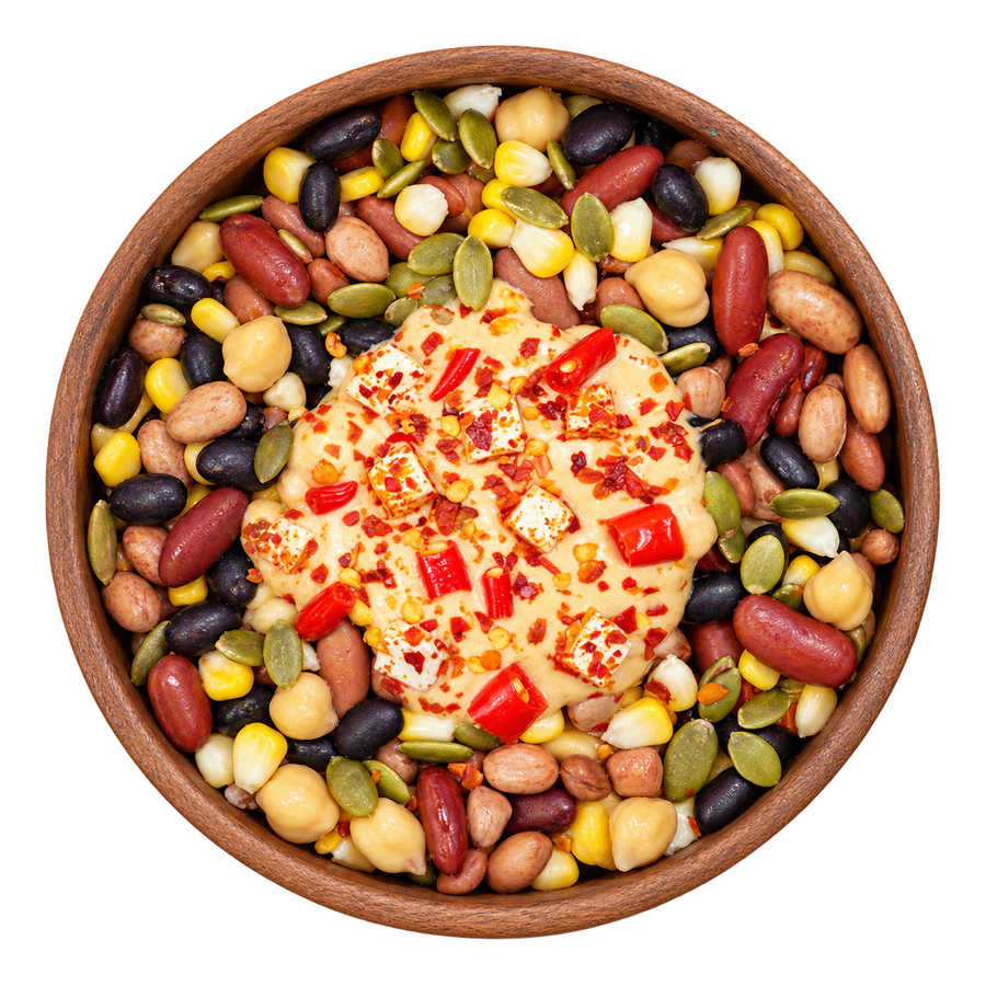 Overhead view of mixed beans, chickpeas, corn, groundnuts and pumpkin seeds in a brown bowl, topped with sweet chilli yogurt, paneer and red chilli